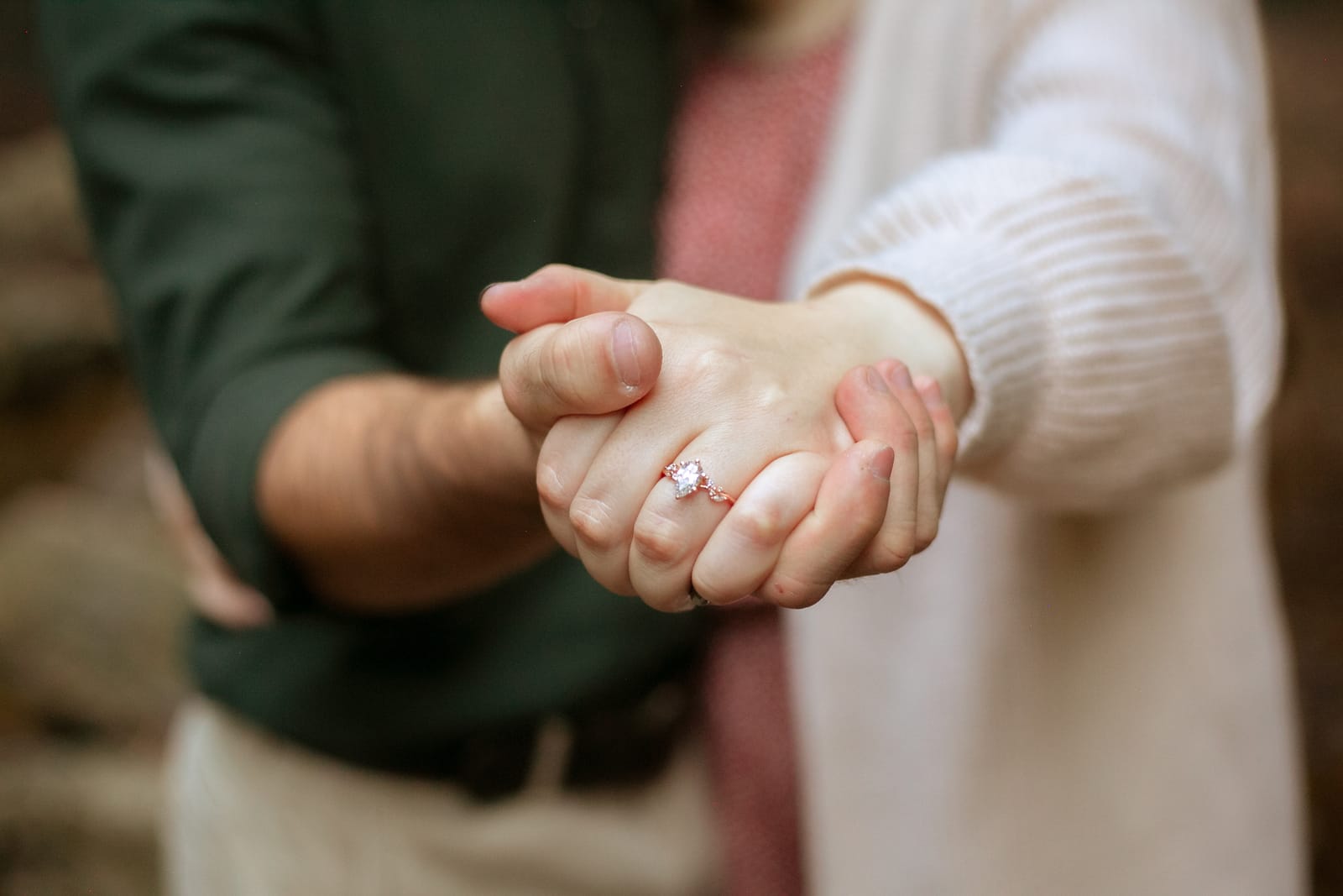 Engagement ring detail on intertwined hands