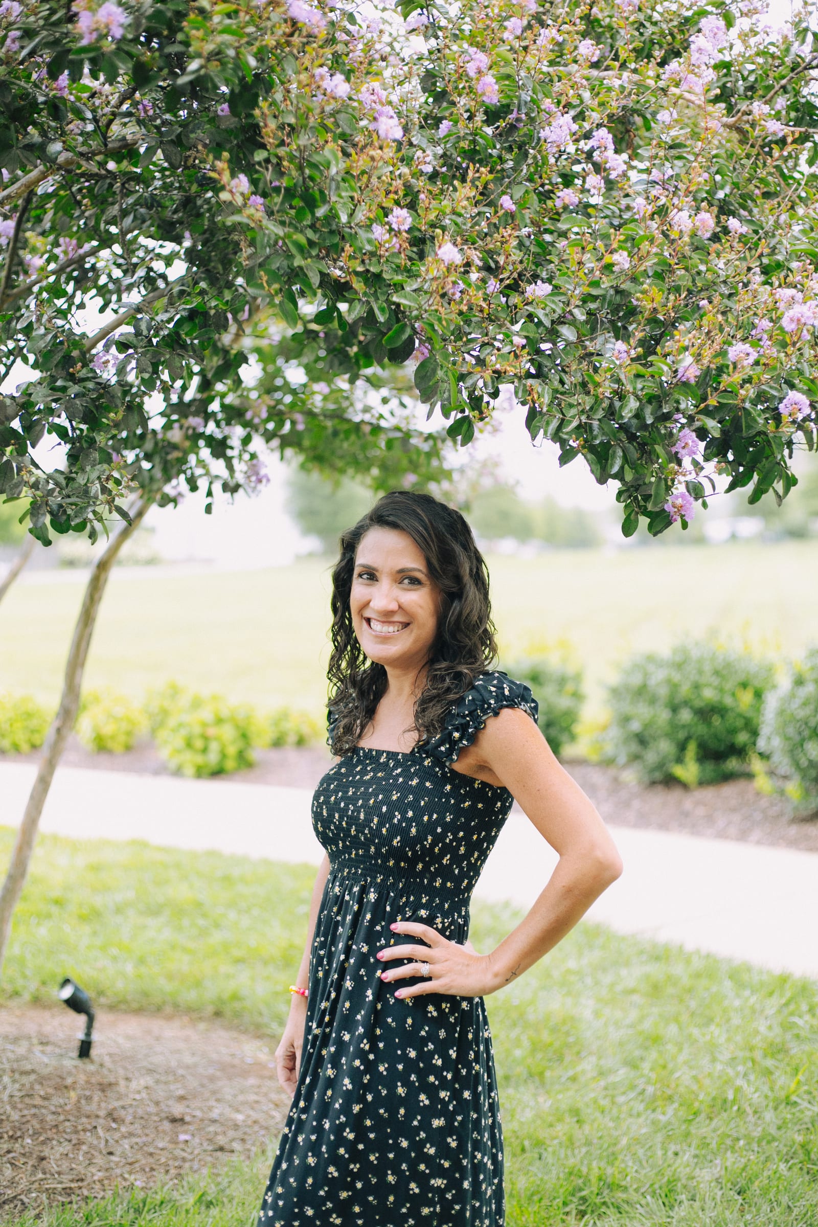 Woman smiling beneath a blooming crape myrtle tree