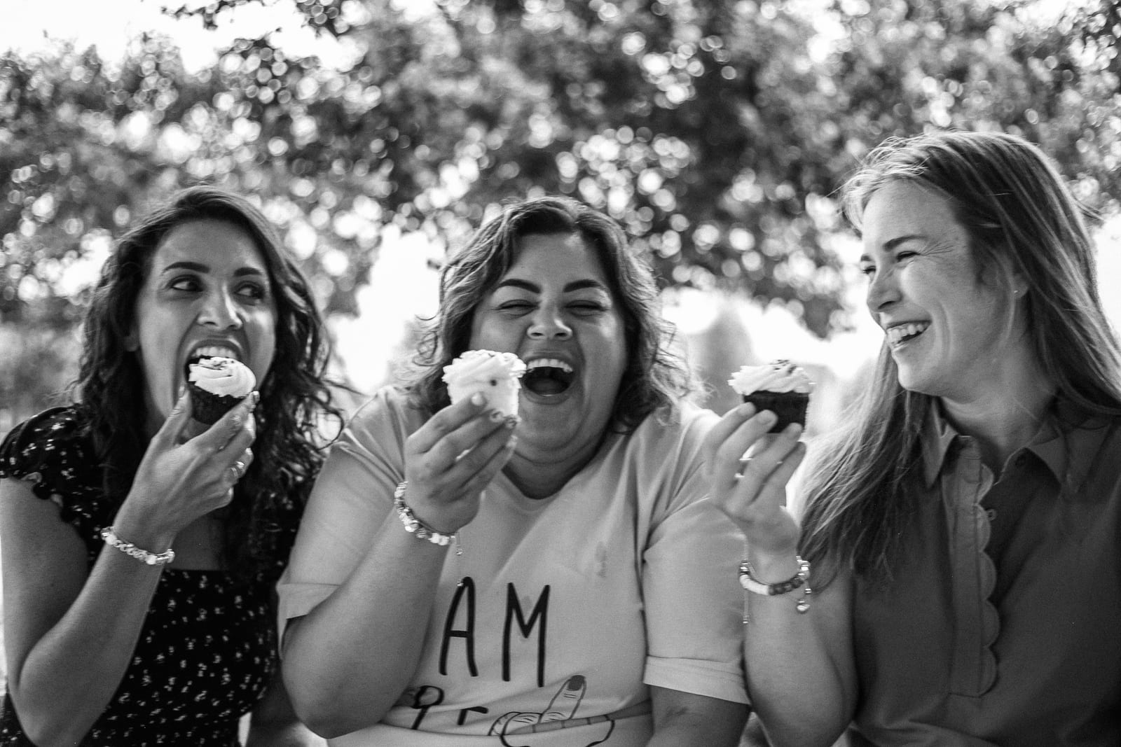 Three friends laughing over cupcakes in black and white