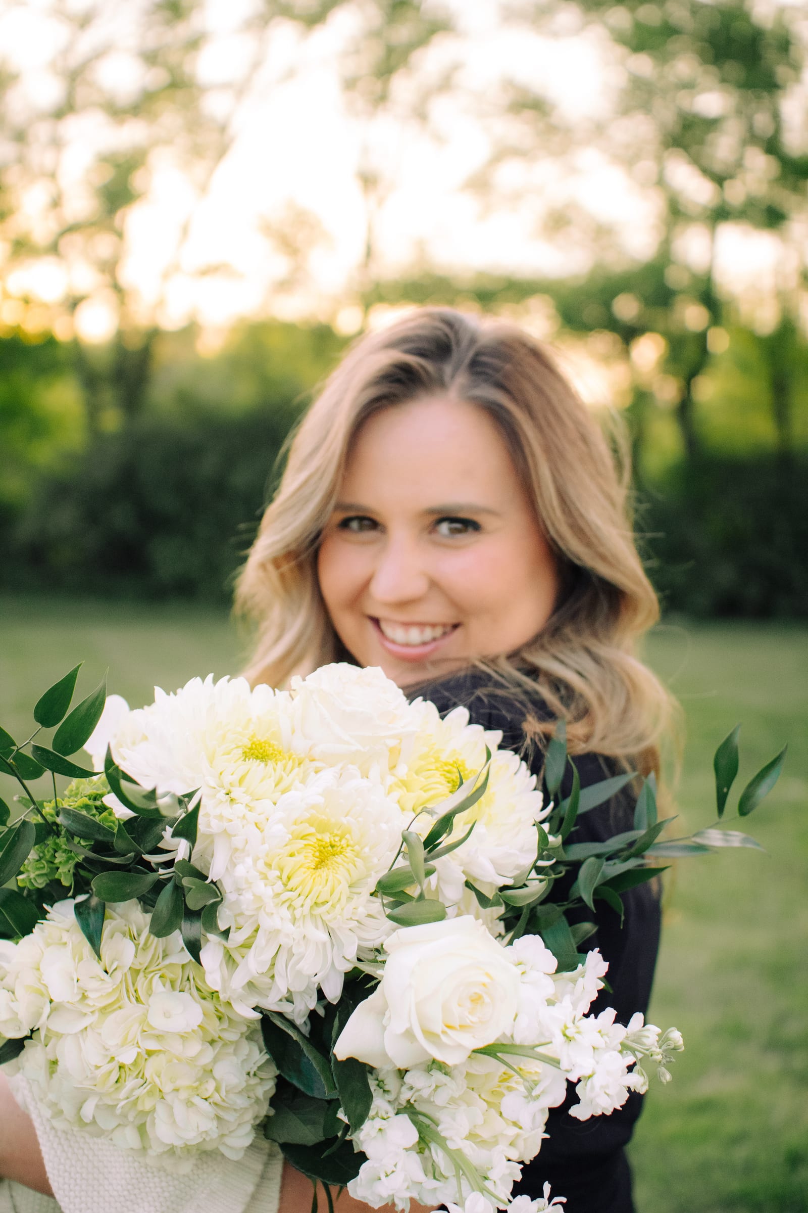 Expecting mother holding a white bouquet at golden hour